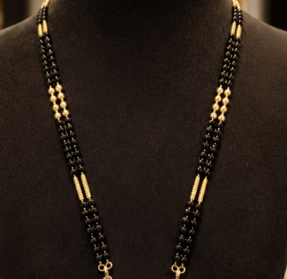 A beaded necklace displayed on a black mannequin bust, featuring black and gold beads with a small gold clasp.