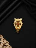 A gold-toned traditional Indian pendant with intricate filigree work, red and black enamel details, and hanging teardrop charms, displayed on a black satin fabric background.